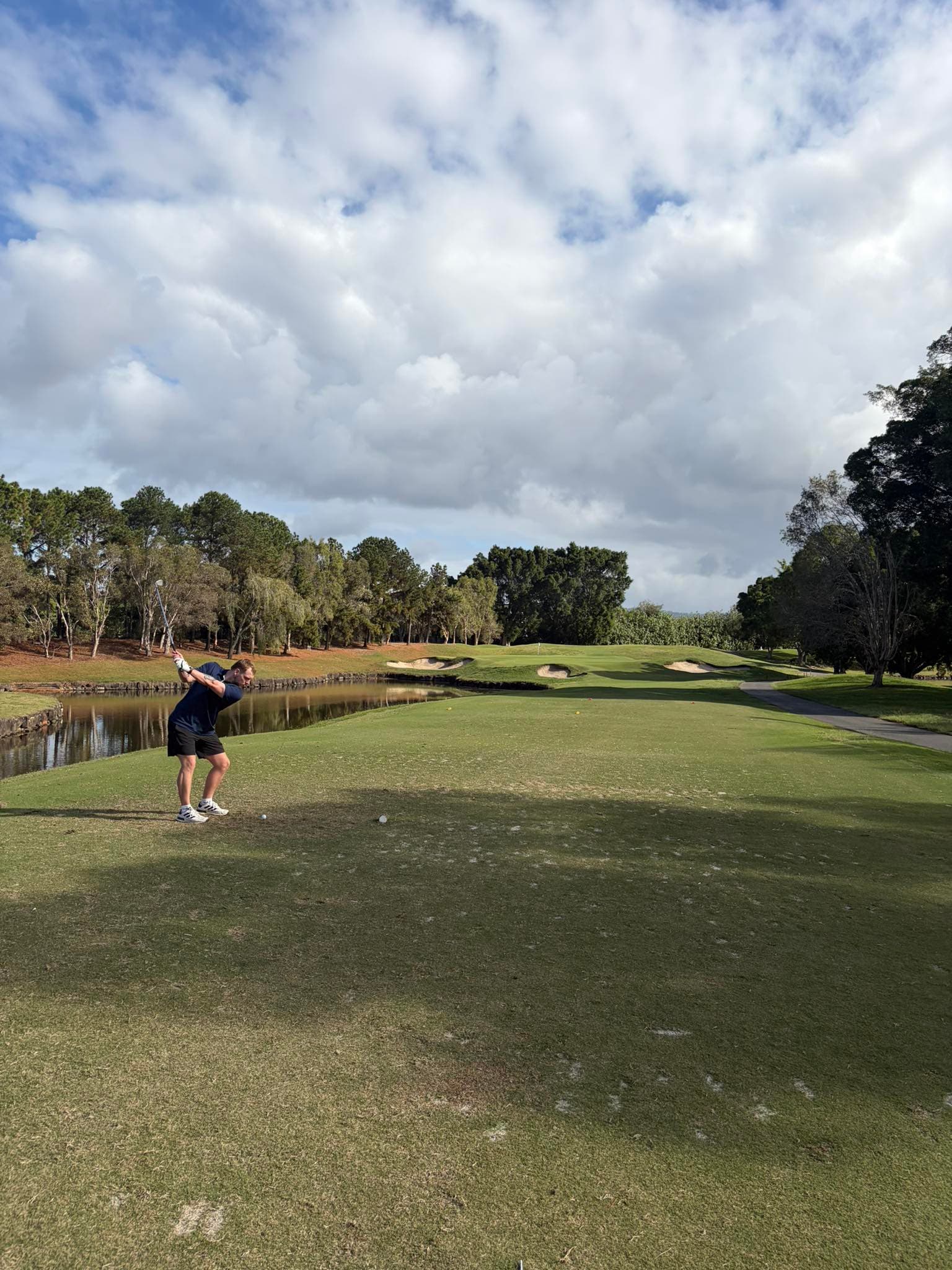 A golfer mid-swing on a course fairway